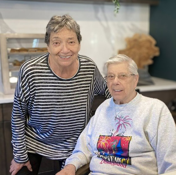 Two seniors smile together in the bistro area of The Barrymore Senior Living.