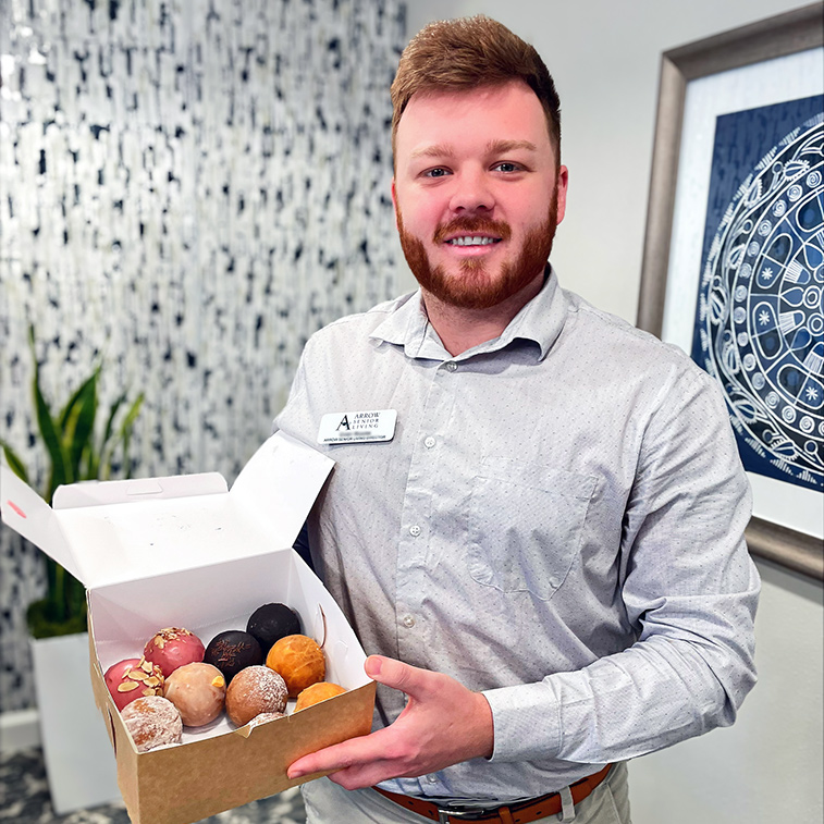A man on the Barrymore team smiles with a box of gourmet pastries.
